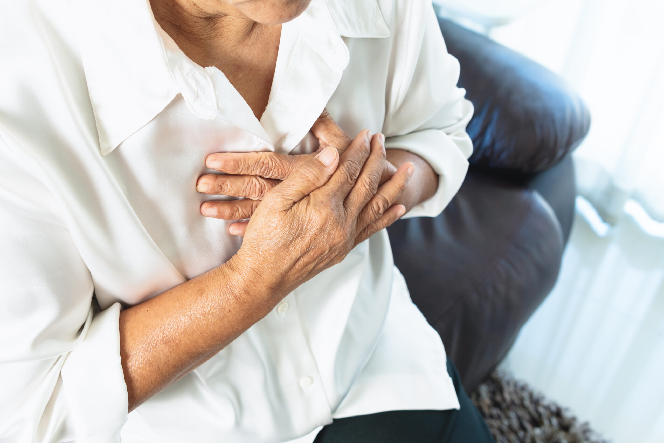 old woman having heart attack grabbing her chest scaled